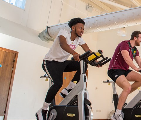 Students on stationary bikes in the gym.