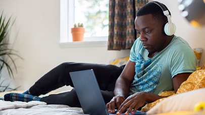 Young male student sitting with laptop in a room