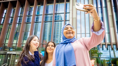 Group of three female students standing outside the University